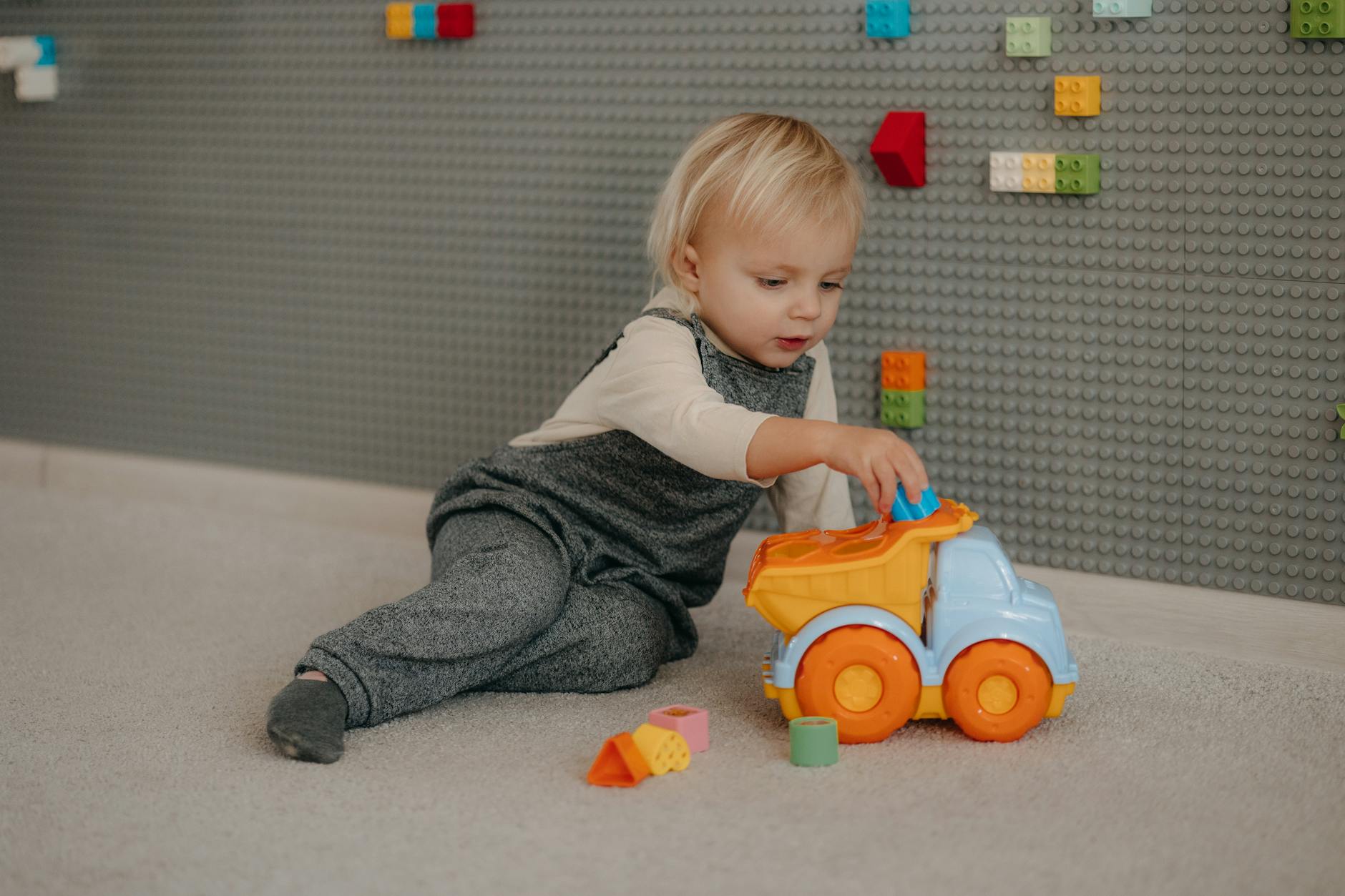 a baby playing with a toy truck on the floor